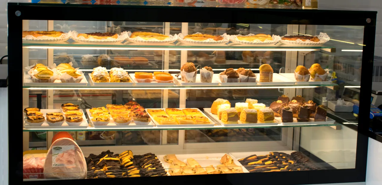 A montra da Doçura da Maia, com quatro prateleiras de bolos e pastéis